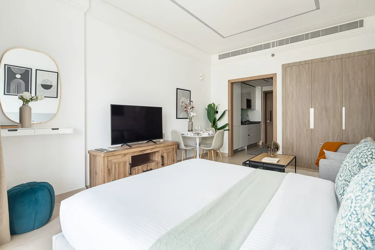 Un dormitorio luminoso con una cama grande, televisor y zona de estar.
