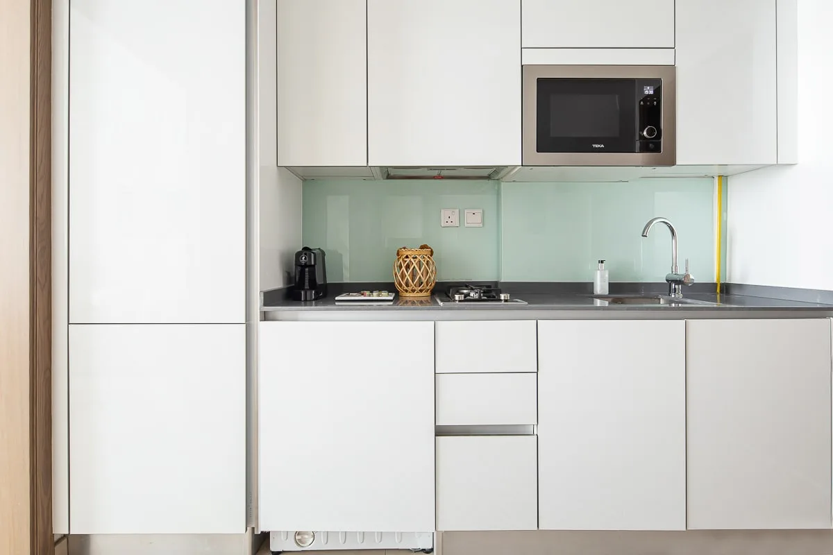 Una cocina compacta con gabinetes blancos, una encimera y un fregadero.