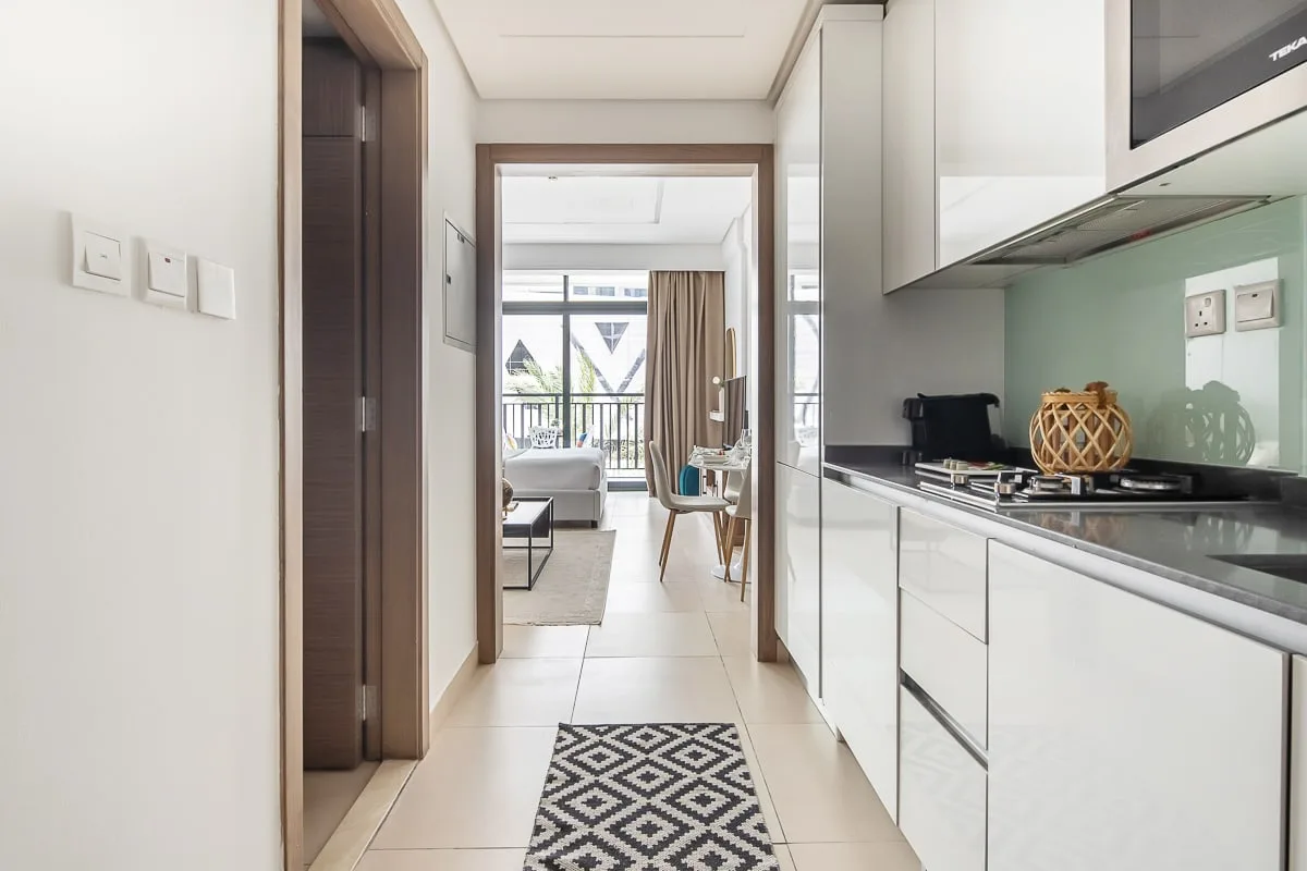 Una cocina luminosa da a una sala de estar con asientos y ventanas grandes.