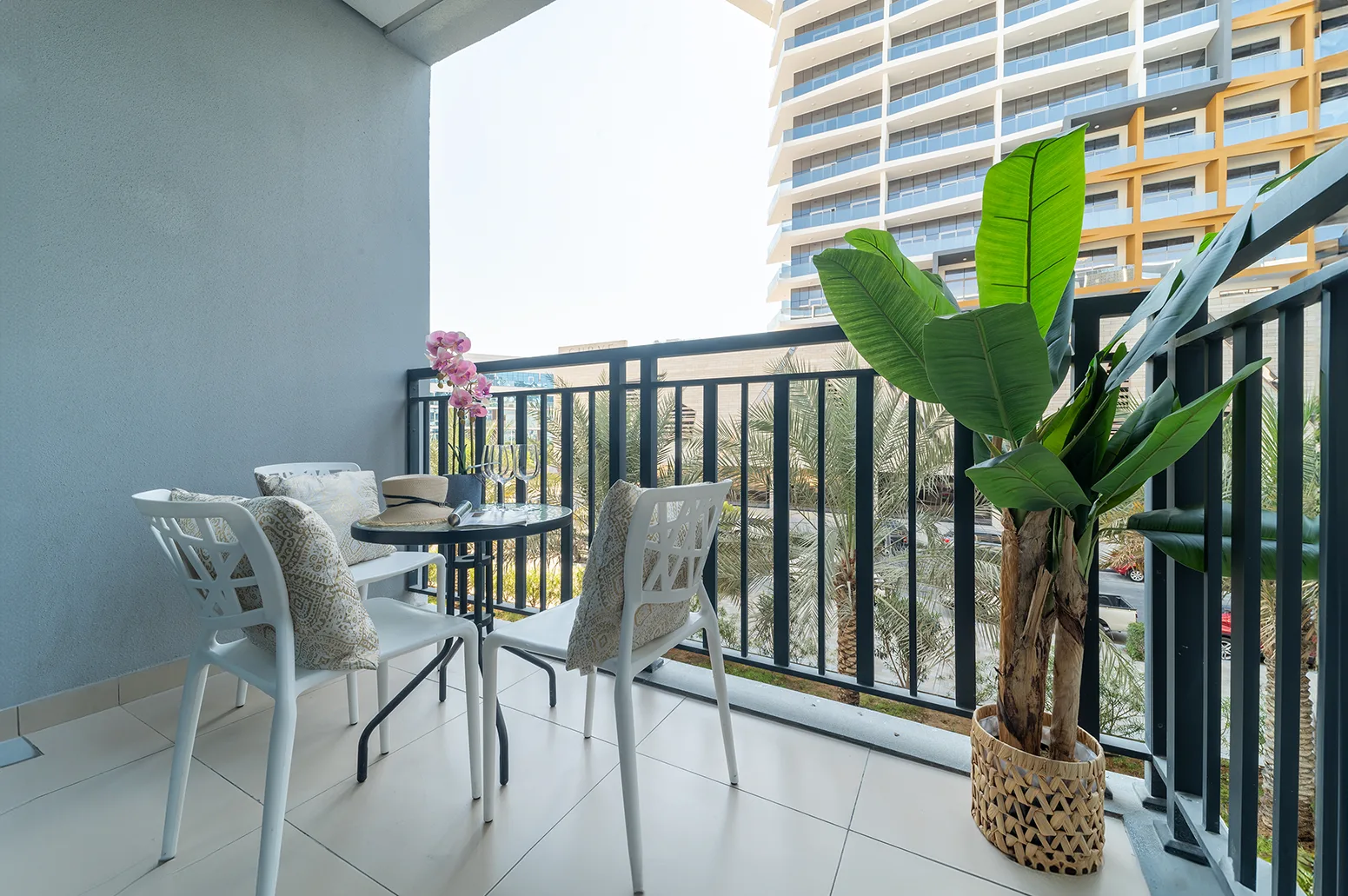 Un área de descanso en un balcón con una mesa pequeña y una planta tropical en maceta.