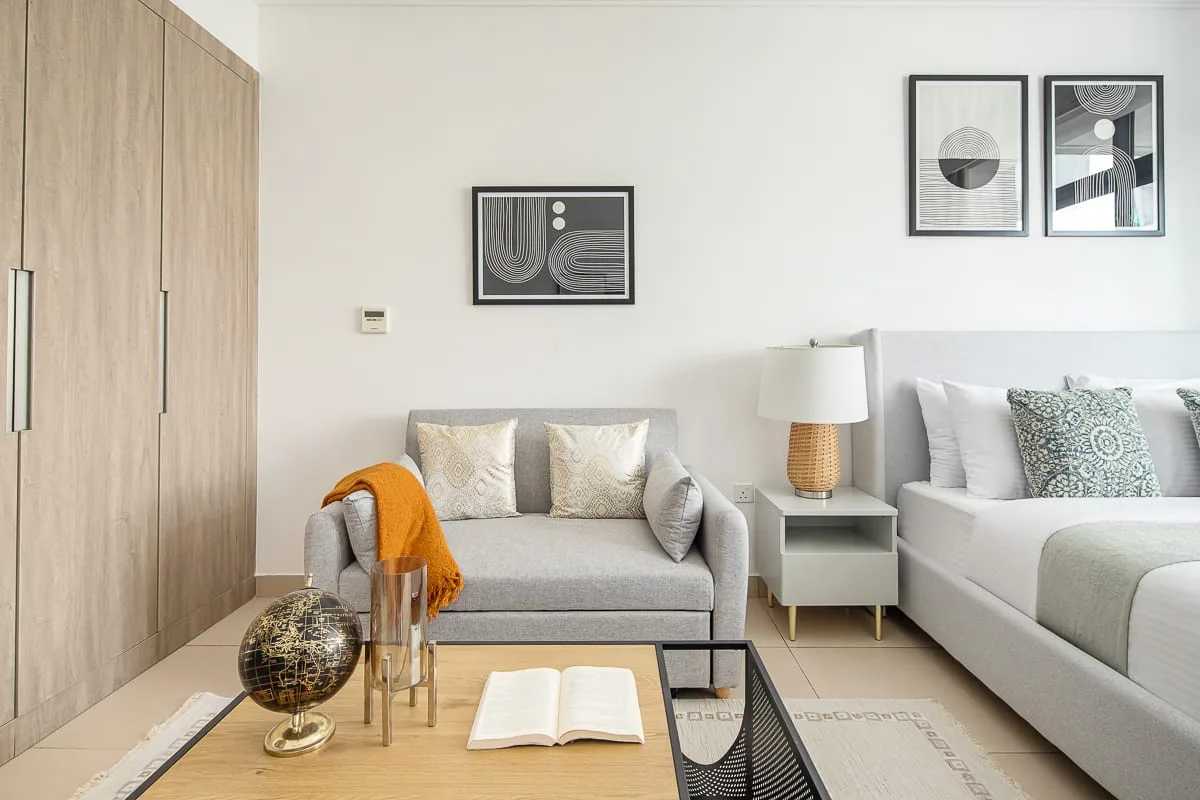 Un dormitorio luminoso con una cama y una pequeña zona de estar.