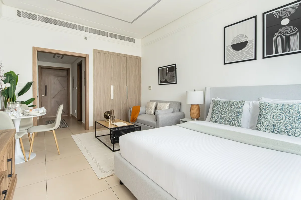 Un dormitorio con una cama grande, una pequeña zona de estar y una mesa de comedor.