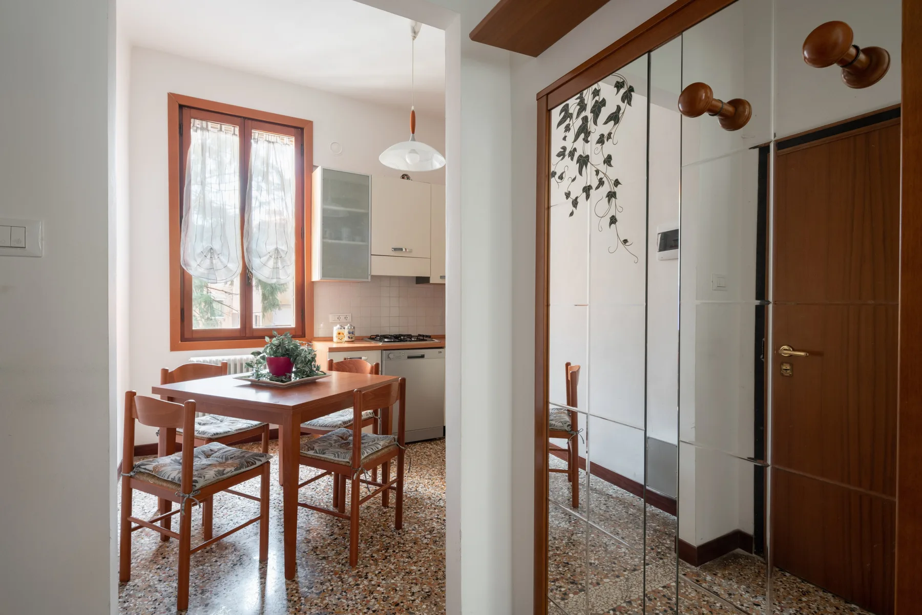 Comedor con una mesa y sillas de madera junto a una cocina compacta.
