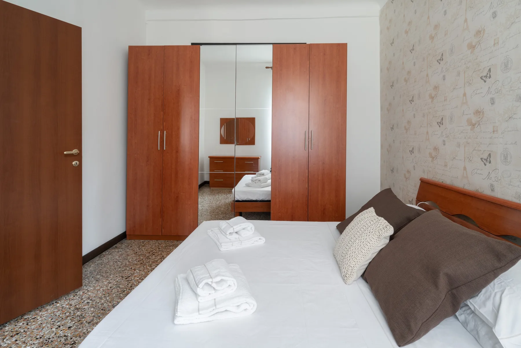 Dormitorio con una cama bien arreglada y armarios de madera.