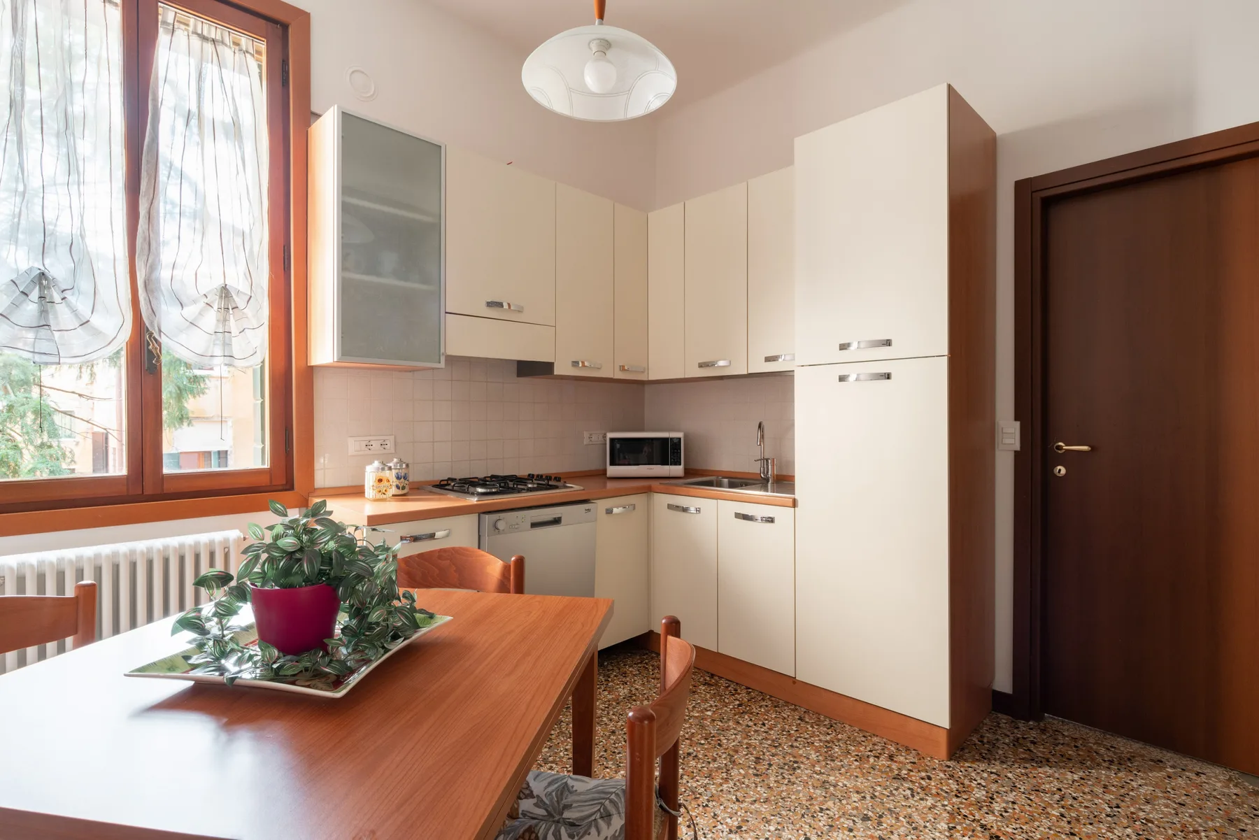 Una cocina con comedor, armarios claros y una mesa de madera.