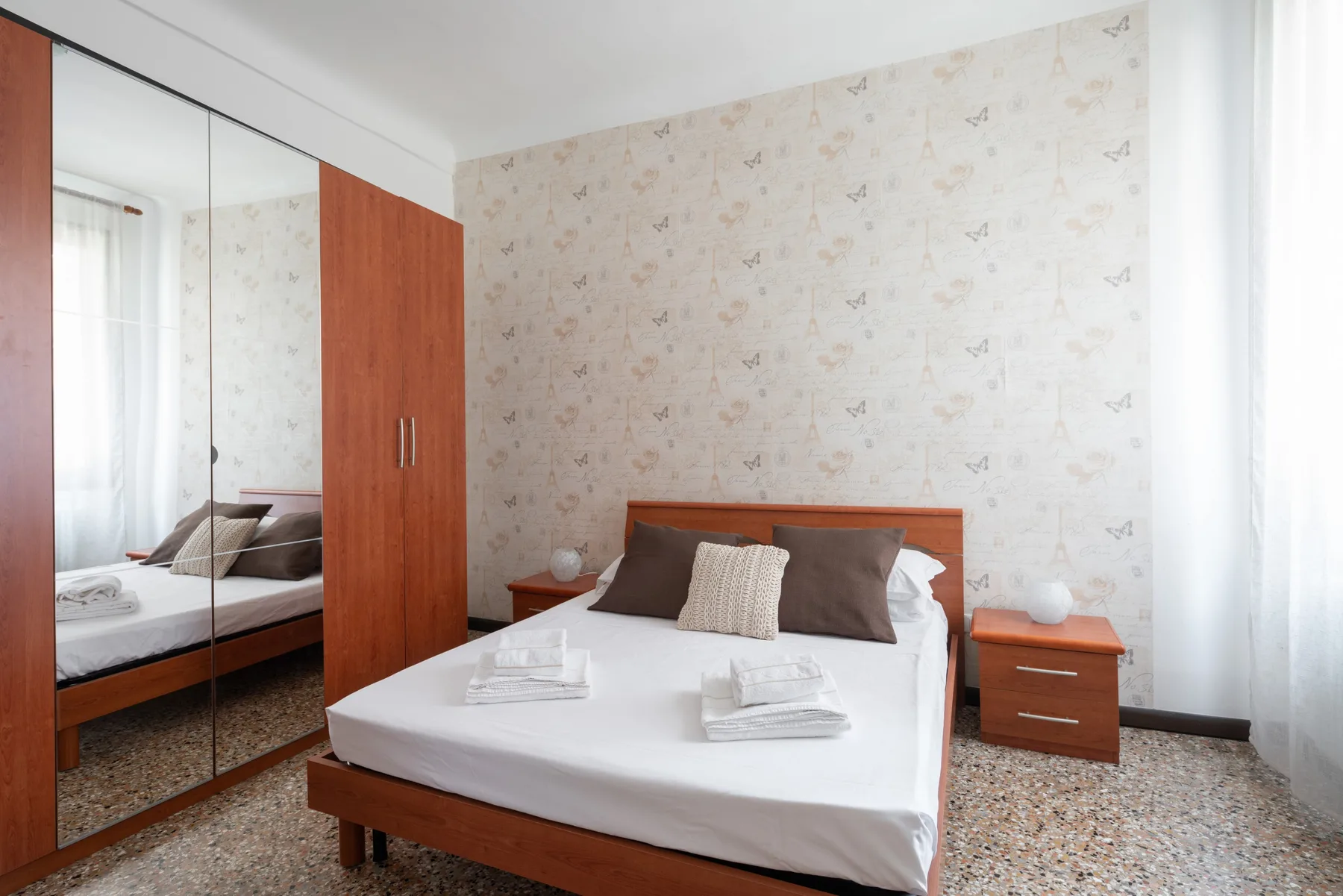 Un dormitorio con una cama tendida y un armario con espejo.