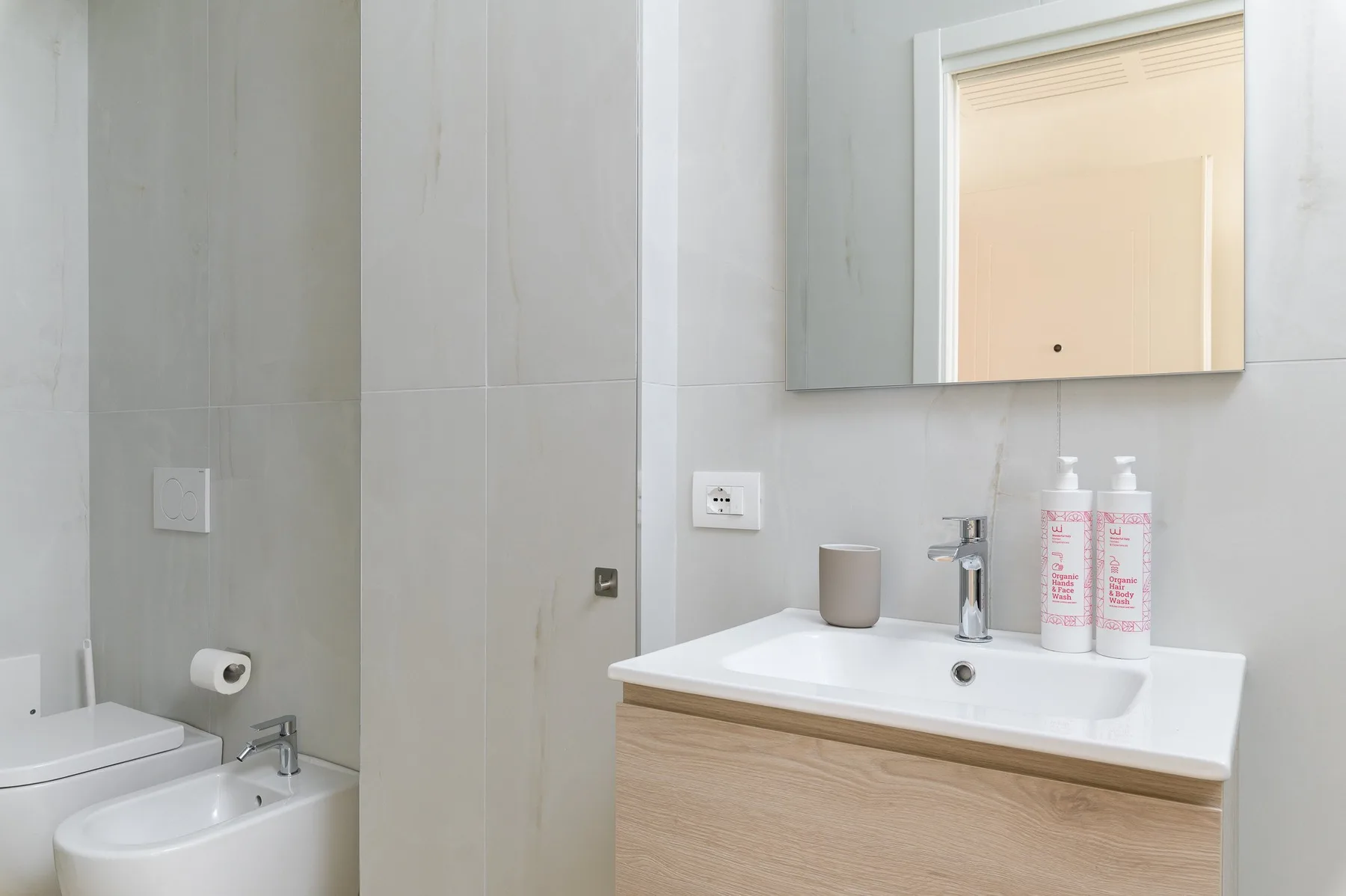Un tocador de baño con lavabo y espejo, junto a un inodoro y una bañera.