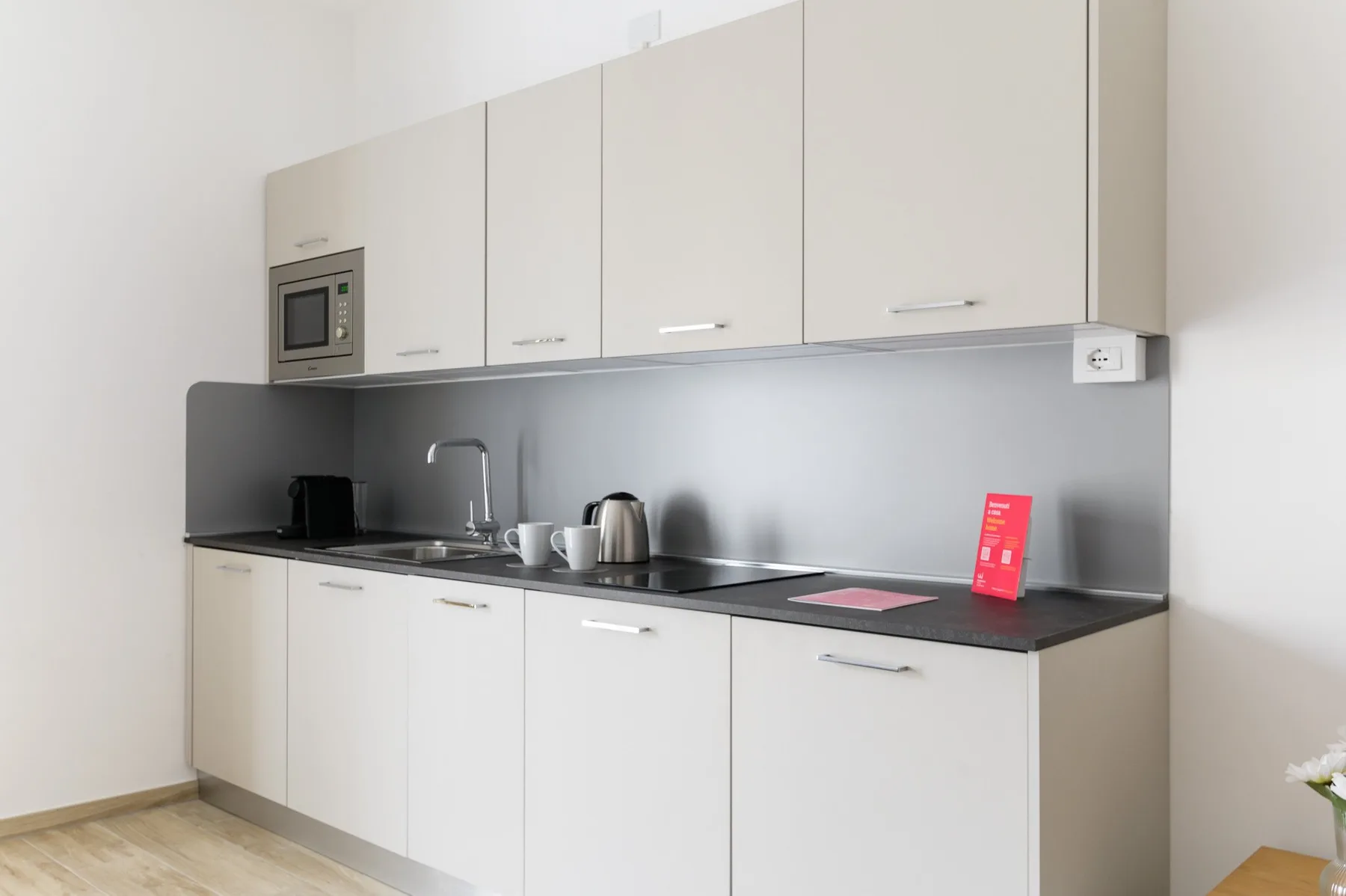 A modern kitchenette with white cabinets, a countertop, and a sink.