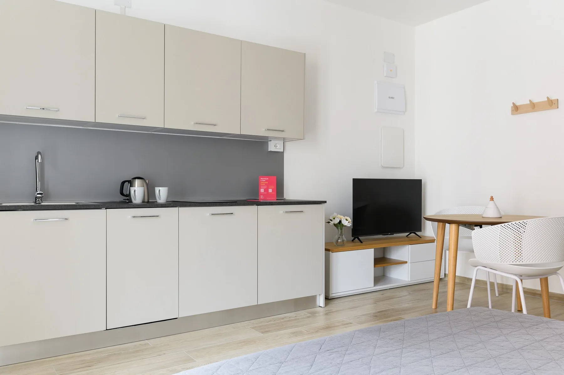 A bright living area with a compact kitchen, television, and dining table.