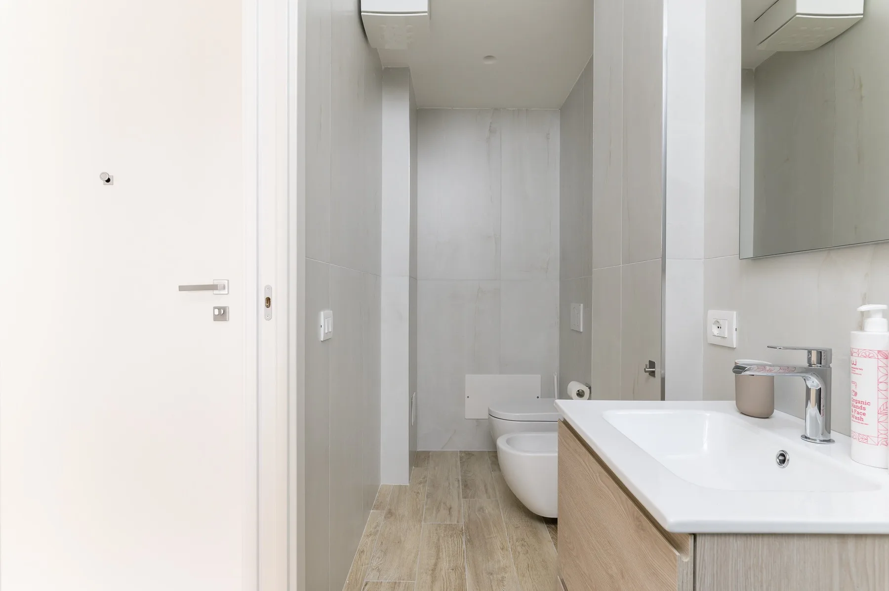Un baño luminoso con lavabo, espejo e inodoro.