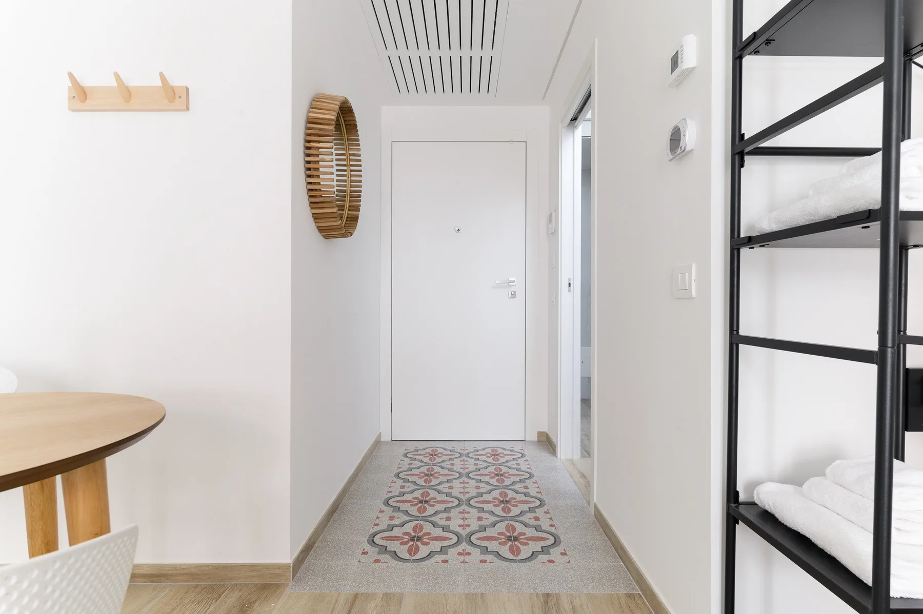 Un pasillo luminoso con una alfombra estampada y una puerta cerrada.