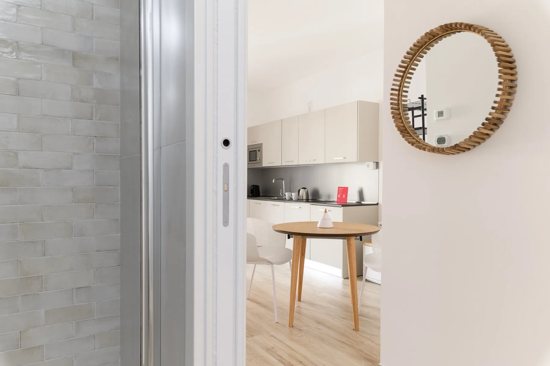 Una cocina luminosa con comedor se ve a través de una puerta abierta.