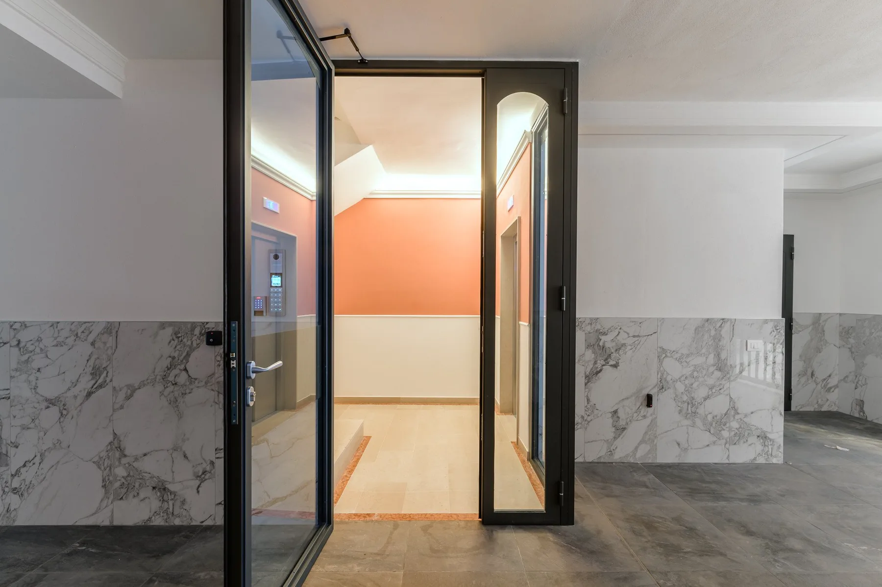 Un pasillo interior con puertas de vidrio y paredes naranjas.
