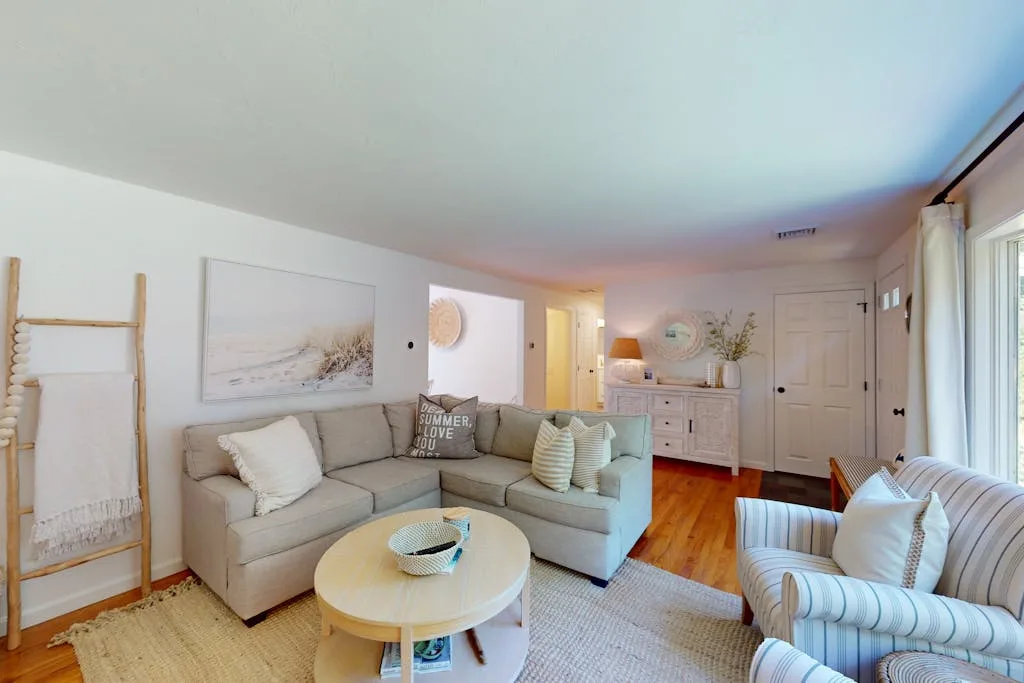 A bright living room with seating, a round coffee table, and a light rug.