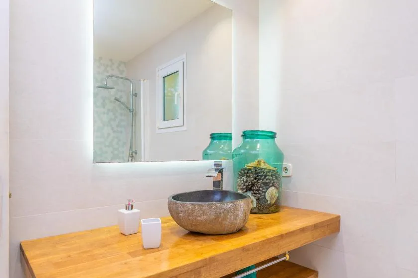 A bathroom vanity with a wooden countertop, basin, and mirror.
