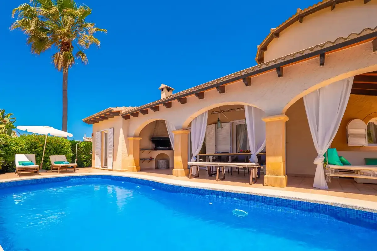 A swimming pool beside a patio with arched openings and outdoor seating.
