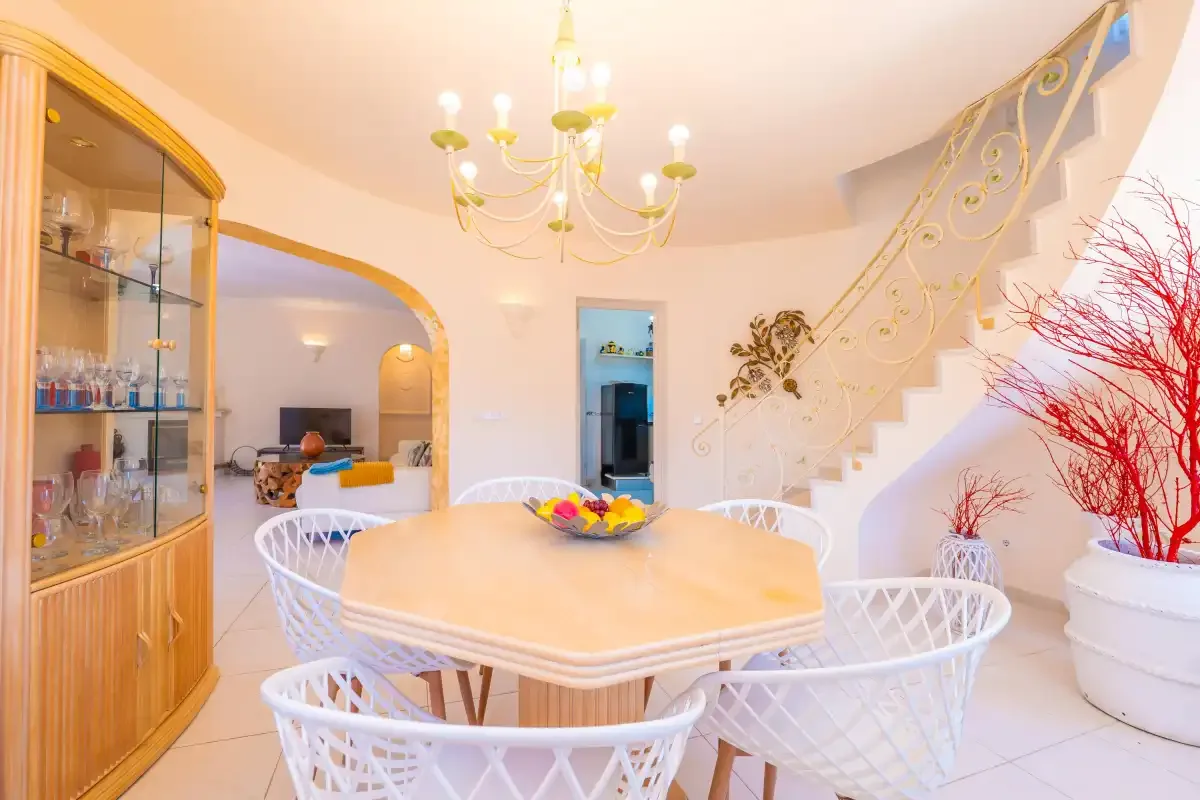 A dining area with a table and chairs beneath a chandelier.