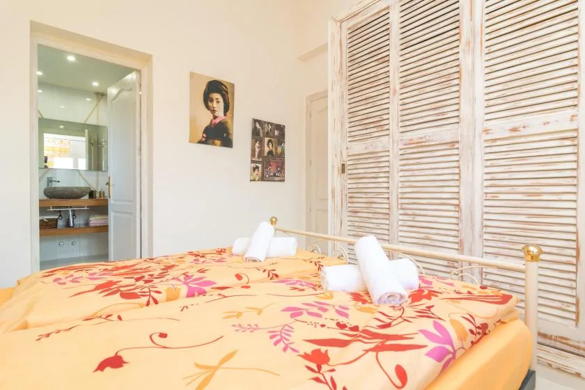 A bedroom with a colorful floral bedspread and white towels.