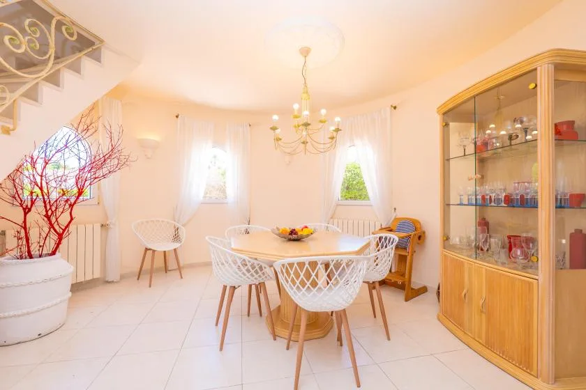 A bright dining room with a round table and a glass-front cabinet.