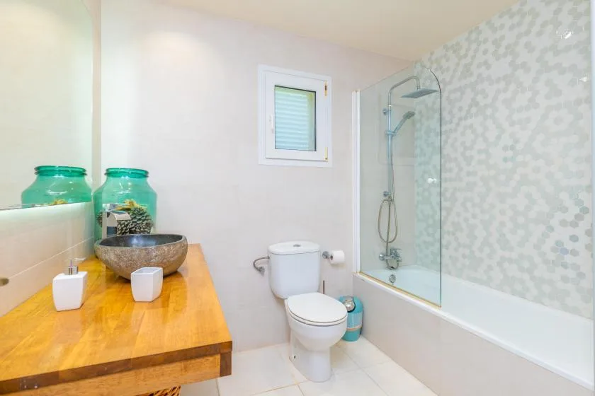 A bathroom with a toilet, bathtub, and wooden vanity.