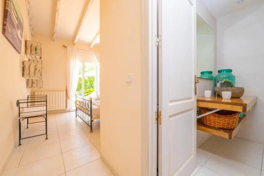 A bright bedroom with a metal bed and a small open pantry beside the doorway.