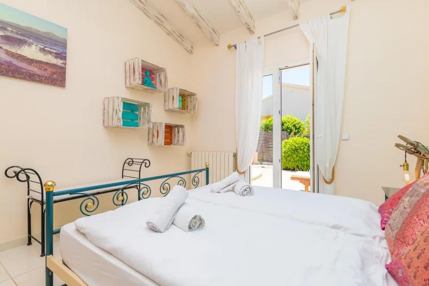 A bright bedroom with a bed beside an open doorway and curtains.