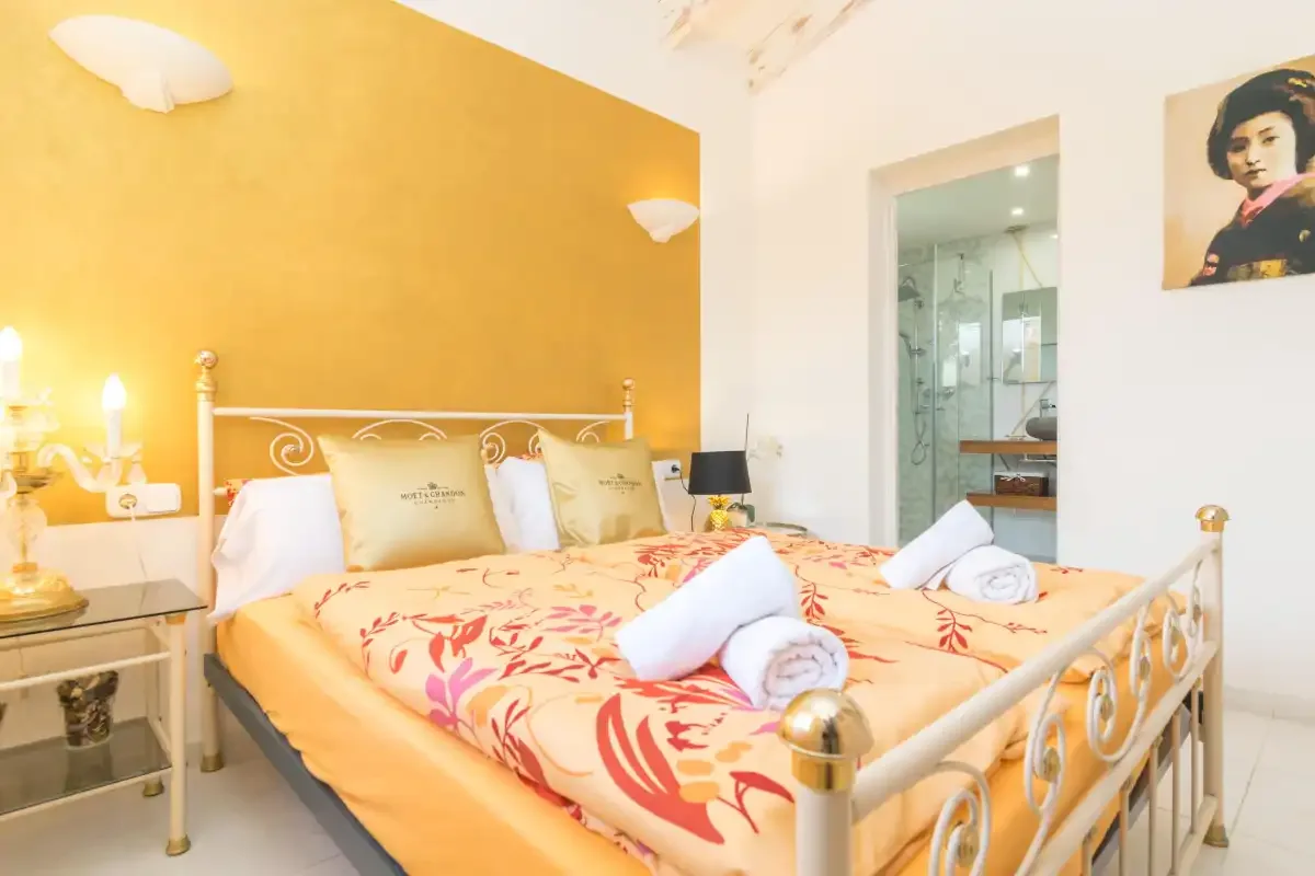 A bedroom with a metal bed, patterned bedding, and a doorway to a bathroom.
