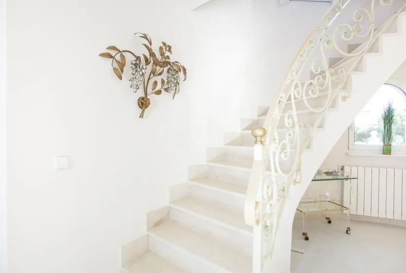 A staircase with an ornate railing beside a bright sitting area.