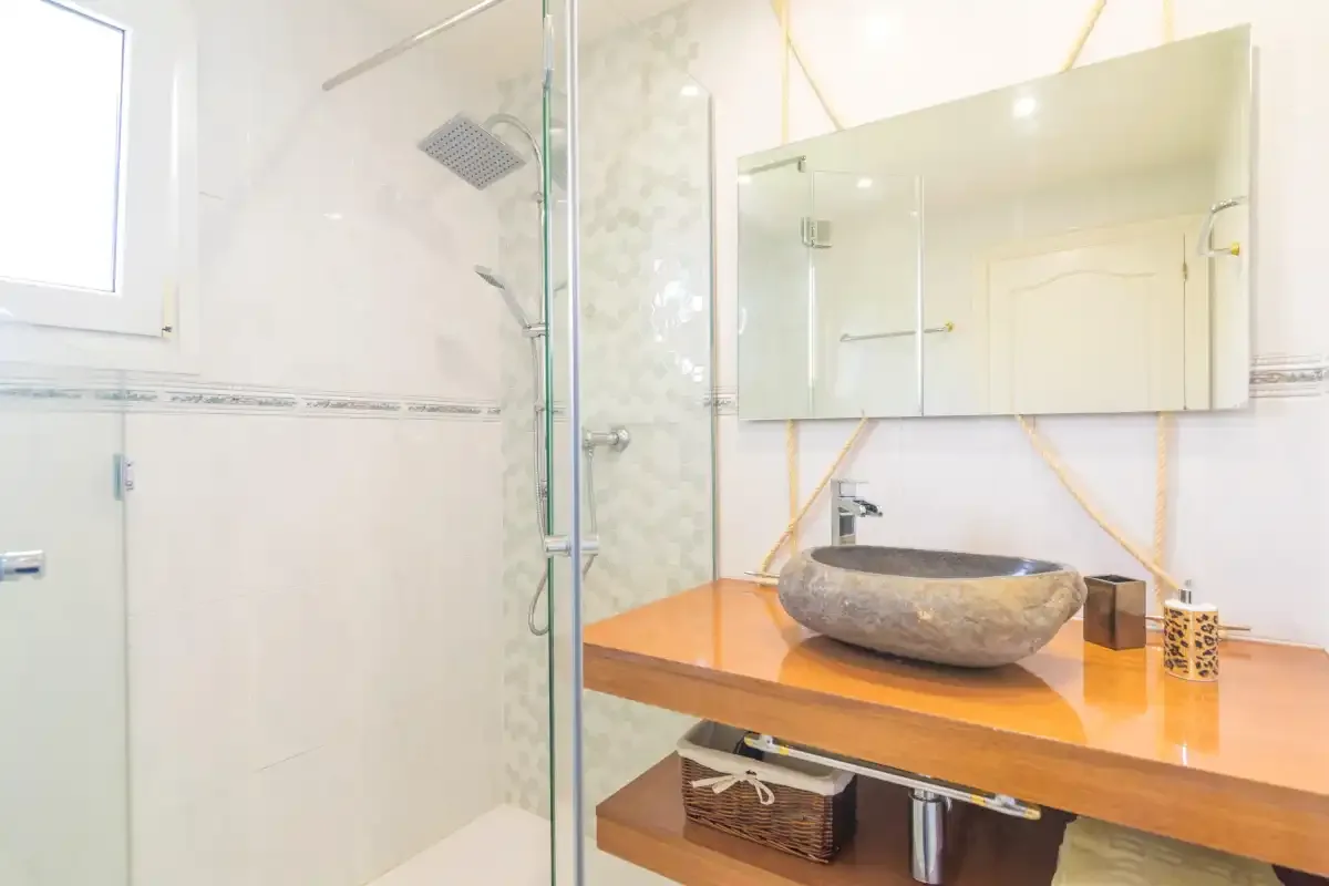 A bright bathroom with a glass shower and a vessel sink on a wooden vanity.