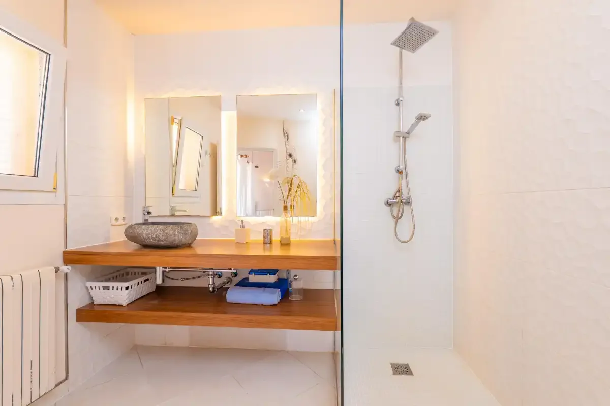 A bright bathroom with a wooden vanity and a walk-in shower.