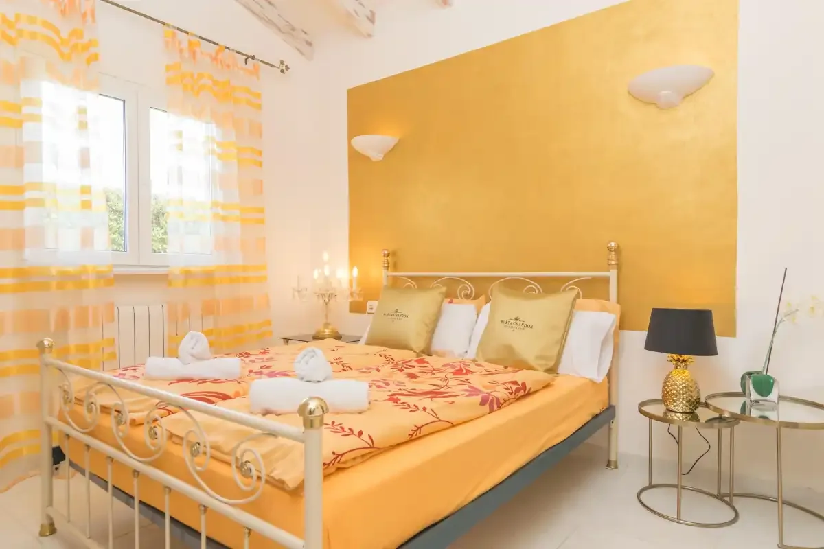 A bedroom with a metal bed, patterned bedding, and a window with striped curtains.