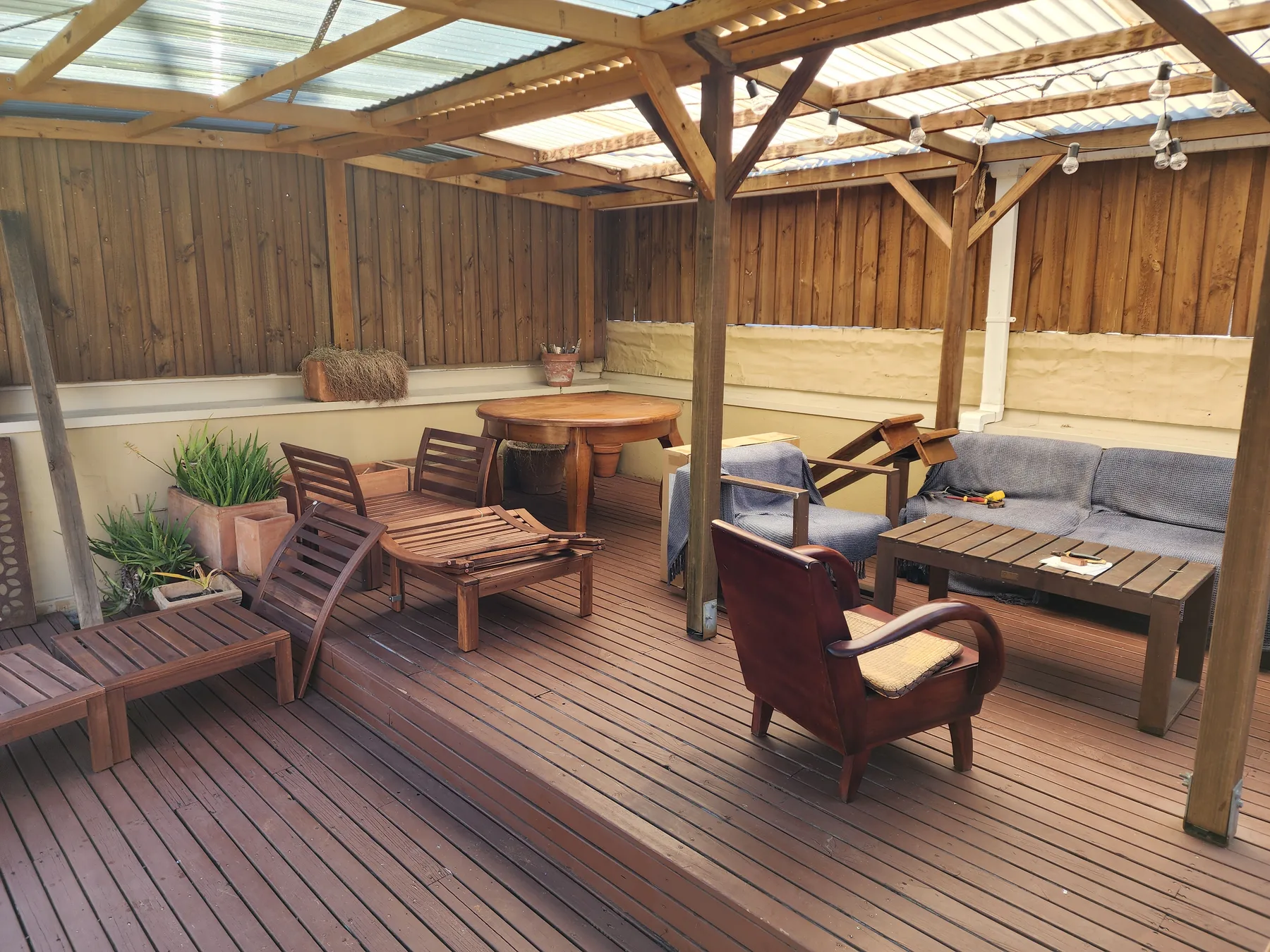 A covered wooden patio with outdoor seating and a low table.