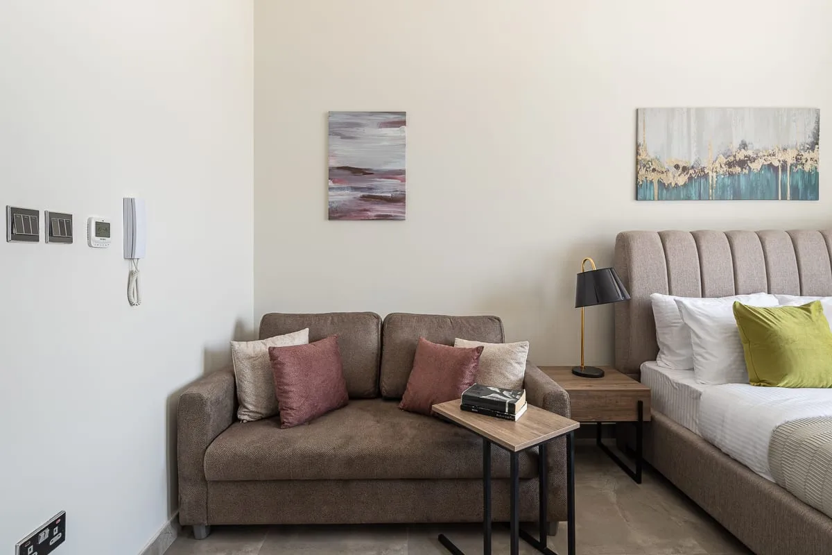 Un dormitorio con una zona de estar junto a la cama y una mesa de centro.