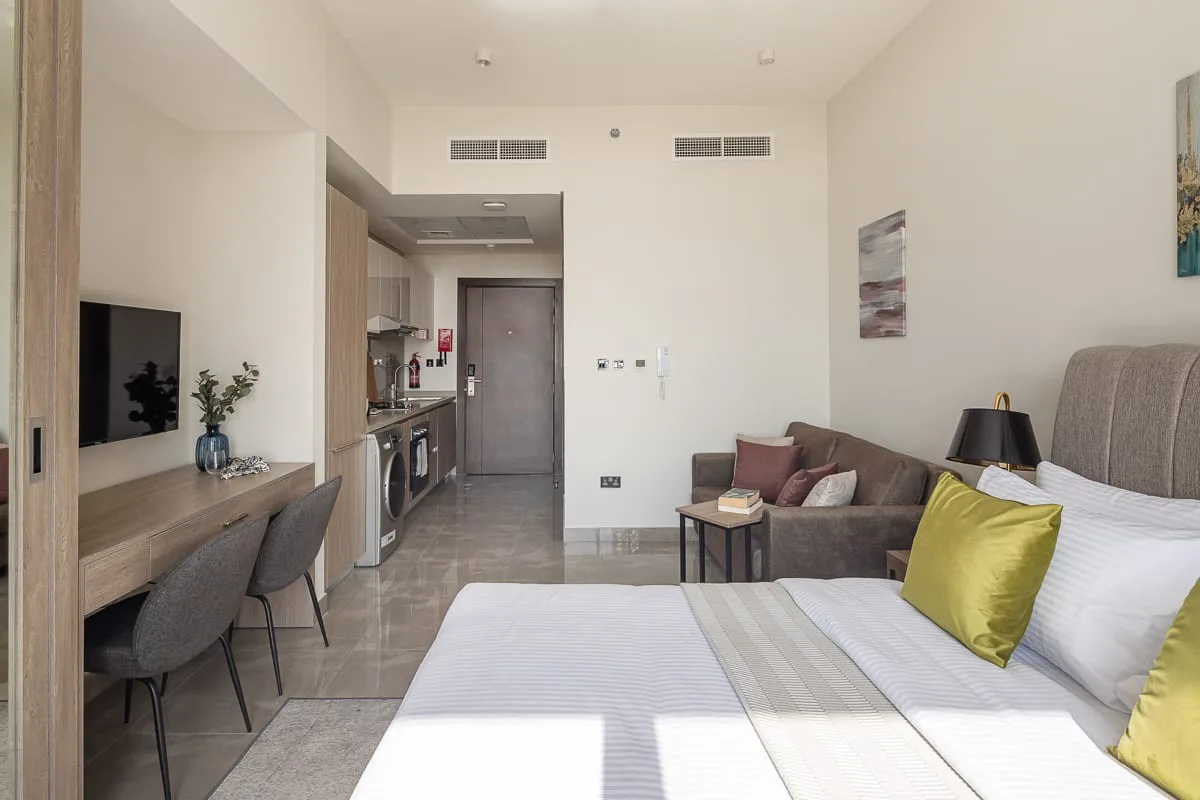 Habitación con cama, sofá y una pequeña zona de cocina.