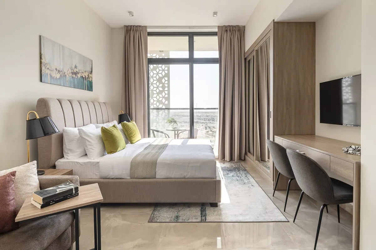 Un dormitorio con una cama, sillas de escritorio y una ventana grande.