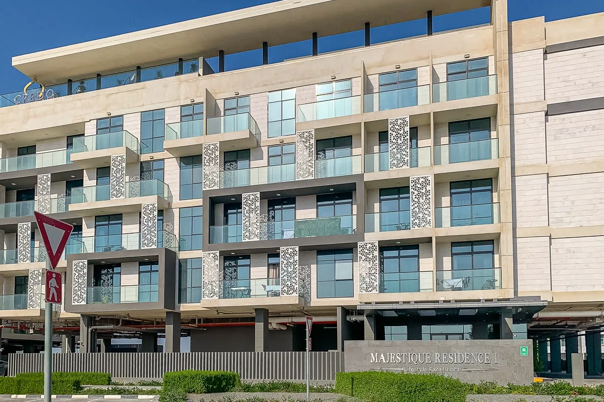 Edificio residencial moderno de varias plantas con balcones de vidrio y jardines.