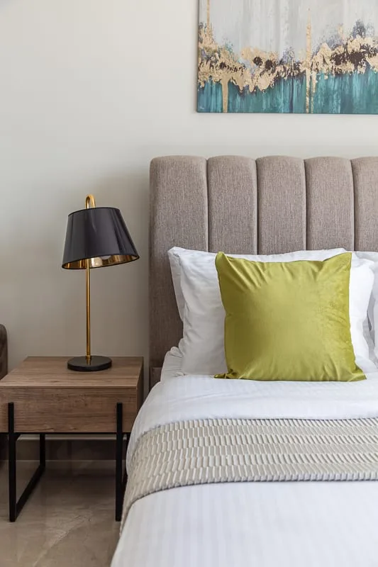 Un dormitorio con una cama bien hecha y un cojín verde.