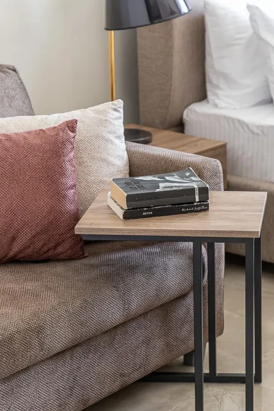 Una zona de estar con sofá, mesa auxiliar y lámpara de pie.
