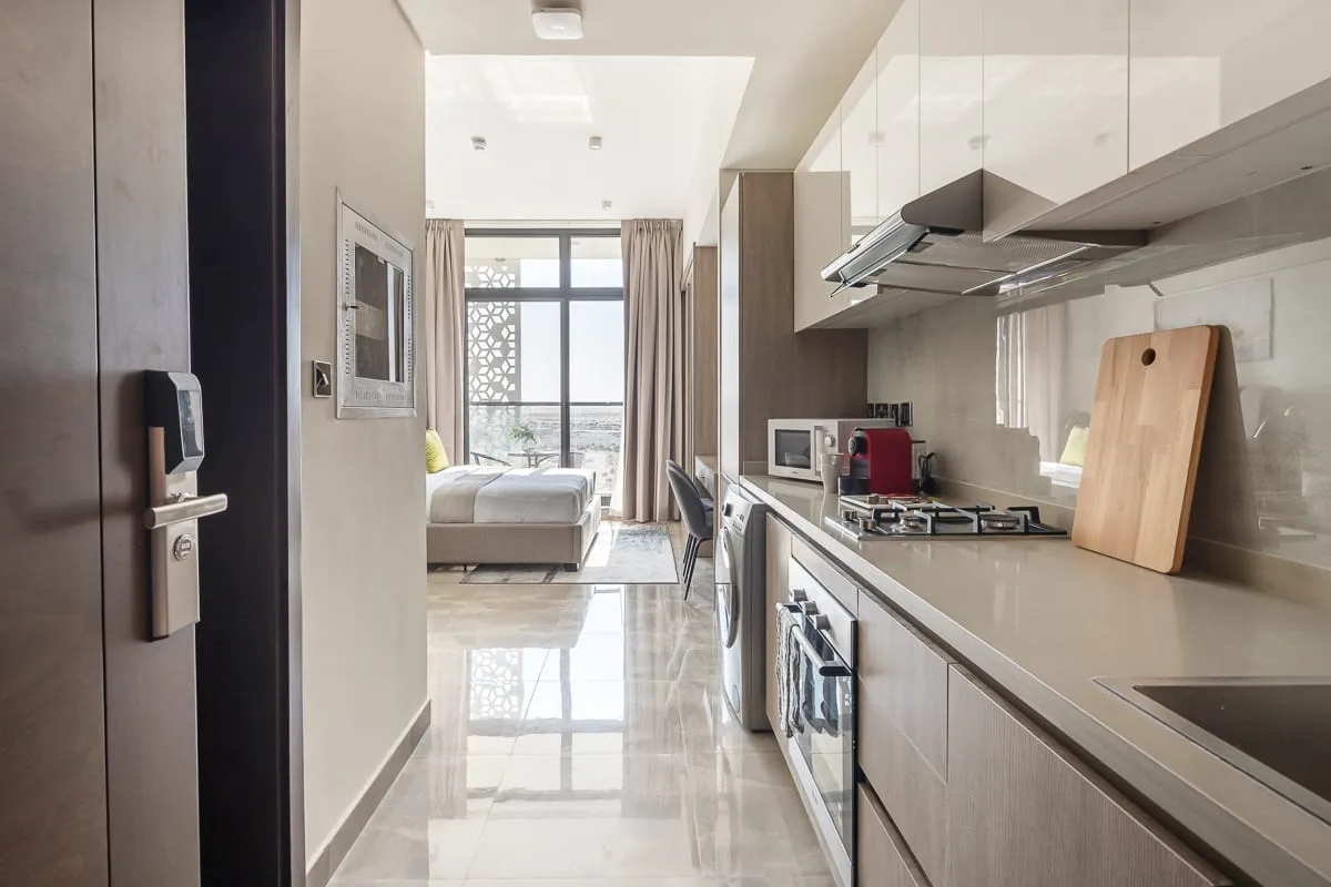 Una cocina moderna se abre a un dormitorio luminoso a través de un pasillo estrecho.