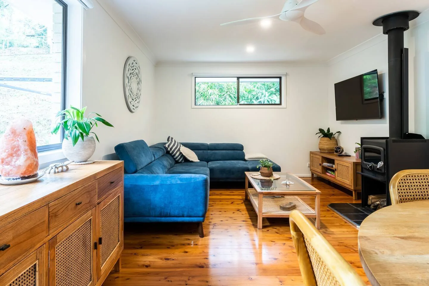Una sala de estar con asientos azules, un televisor y una chimenea interior.