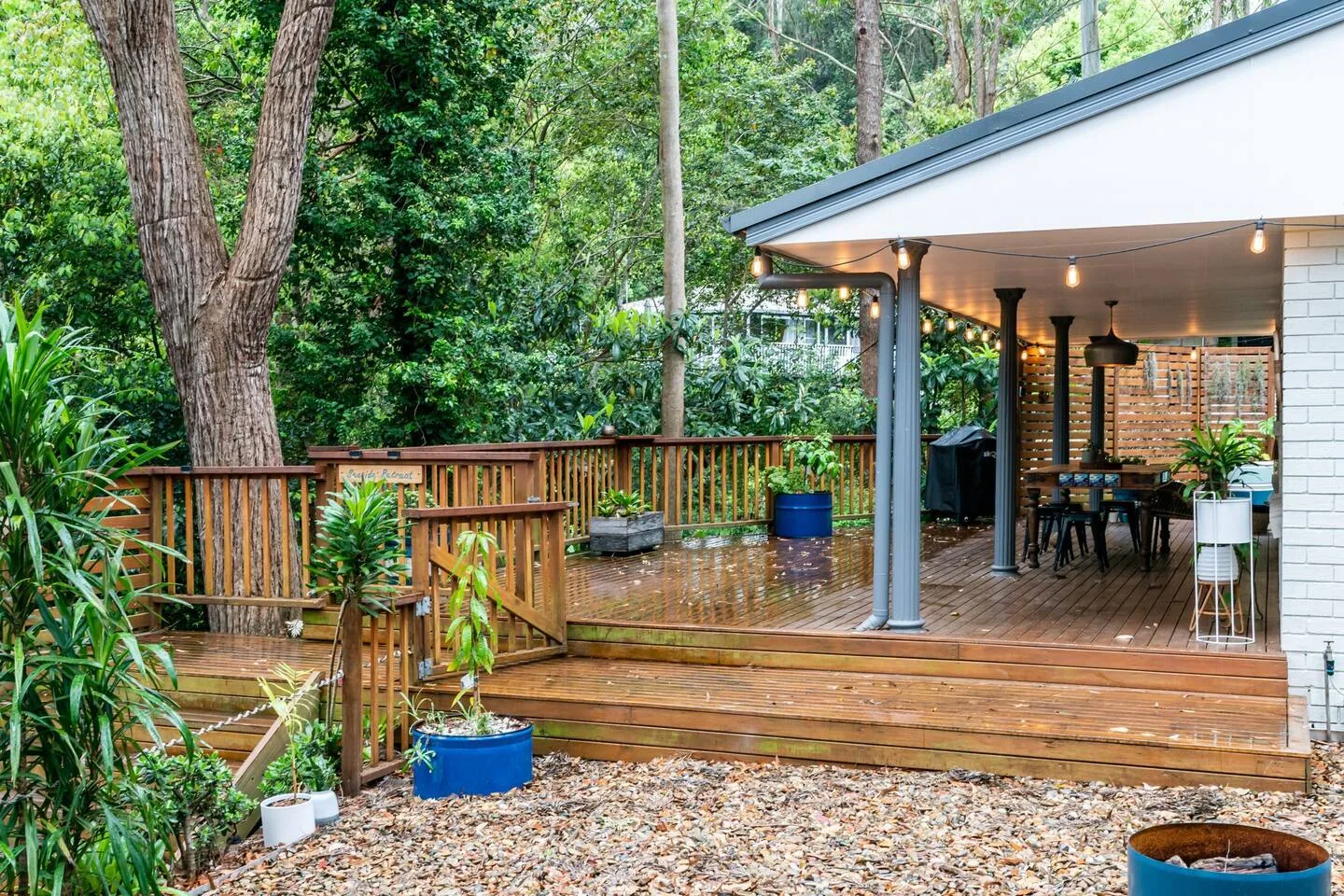 Una terraza cubierta de madera con asientos al aire libre da a un jardín frondoso.