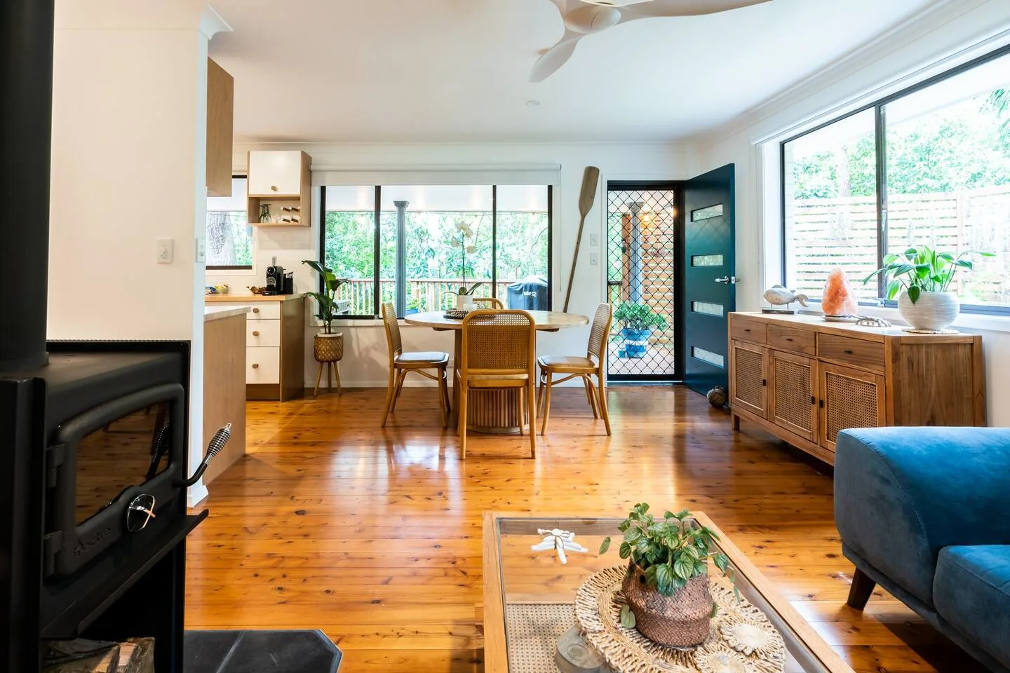 Una luminosa zona abierta de comedor y estar, con una mesa de madera y grandes ventanas.