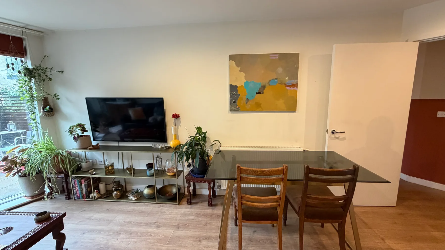Comedor con mesa y sillas junto a un televisor y una ventana.