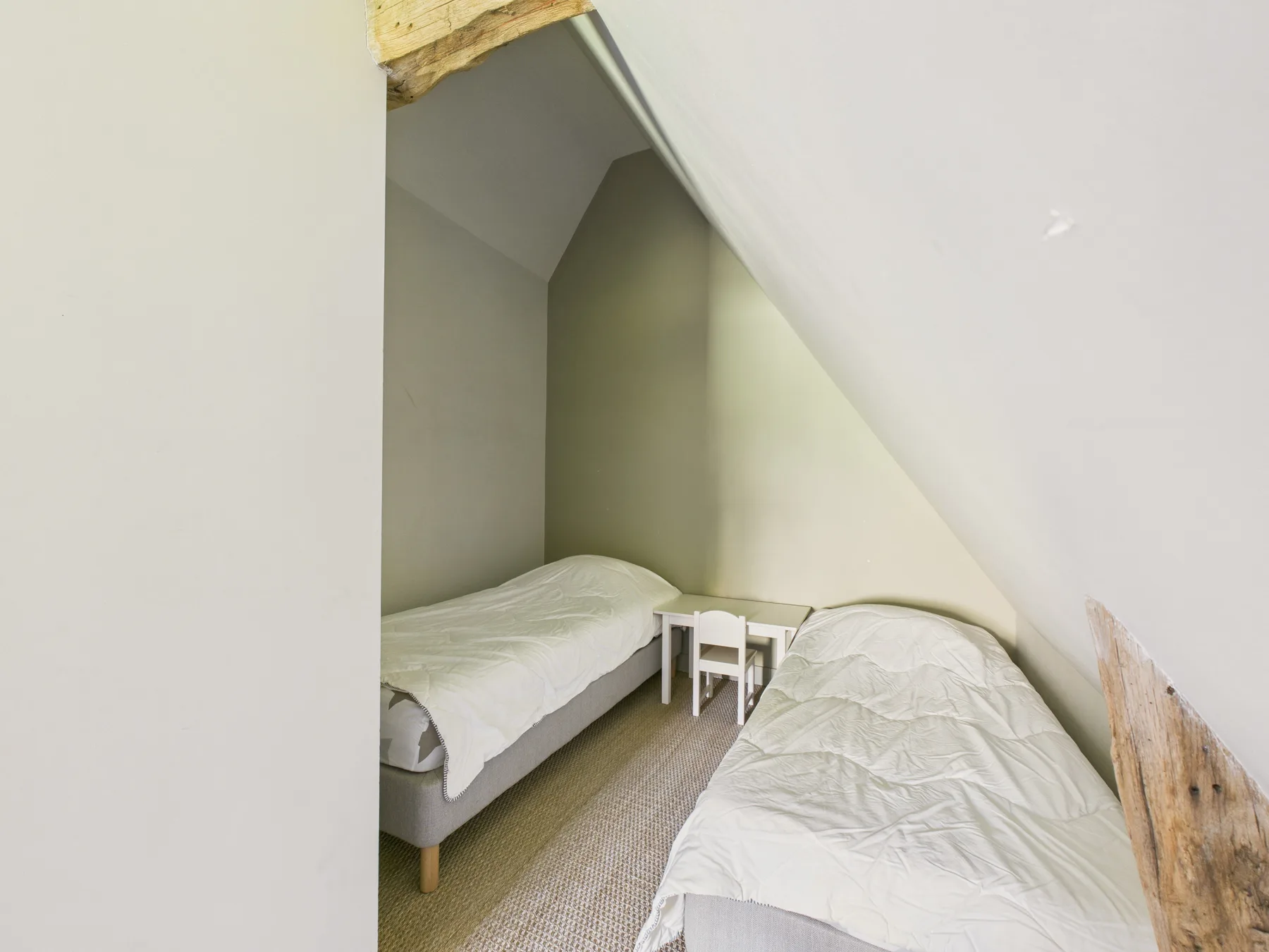 A small attic bedroom with two beds beneath a sloped ceiling.