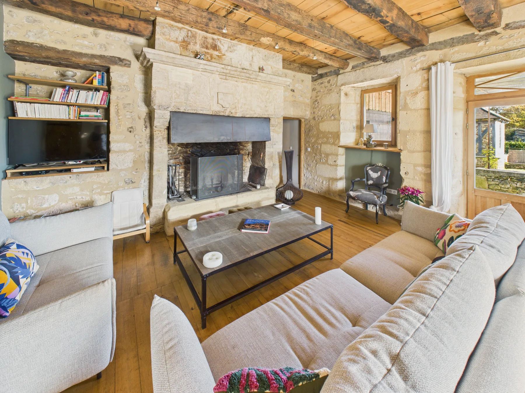 Una sala de estar con una chimenea de piedra y asientos alrededor de una mesa de centro.