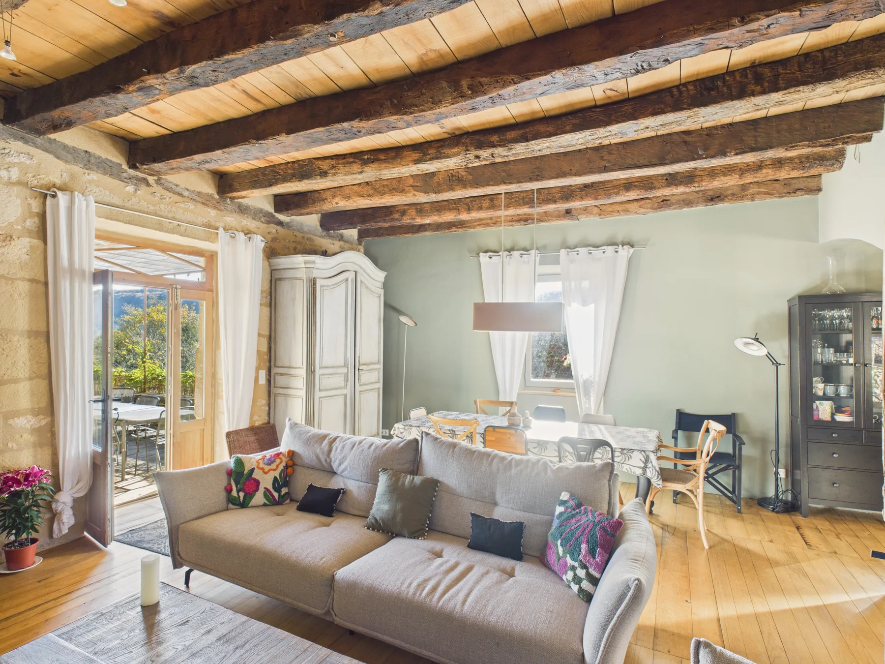 A living room with seating beneath exposed wooden ceiling beams.