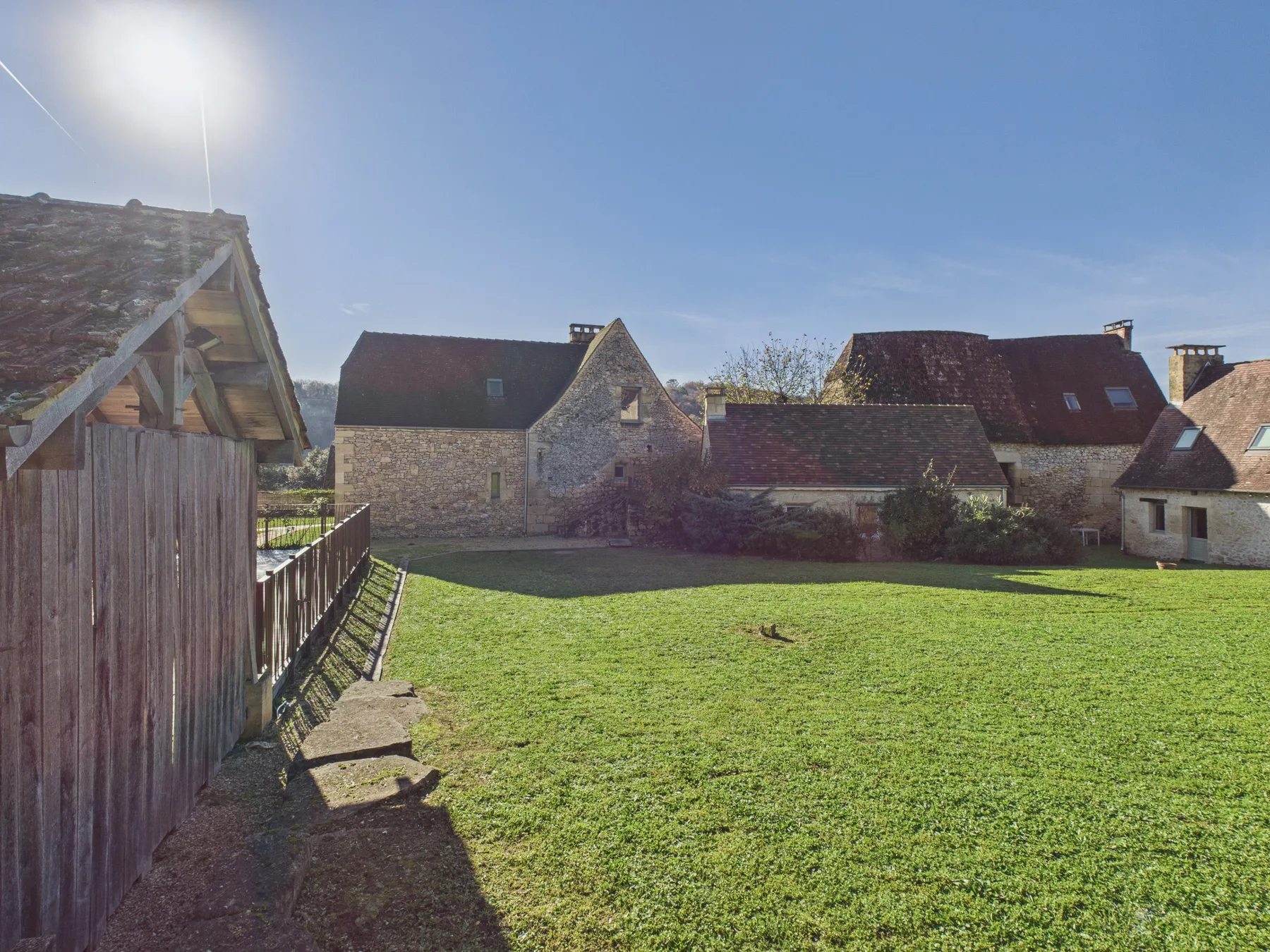 A grassy courtyard sits in front of several stone buildings.