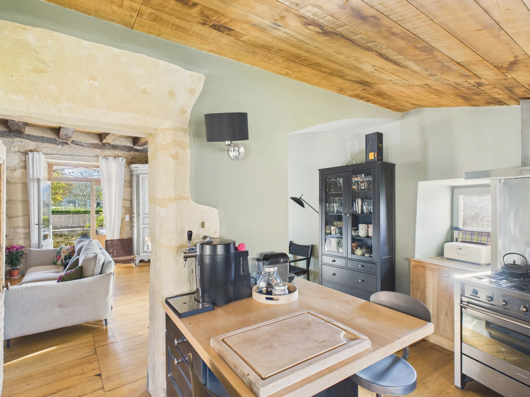 A kitchen with a wooden island and dining seating beneath a sloped ceiling.