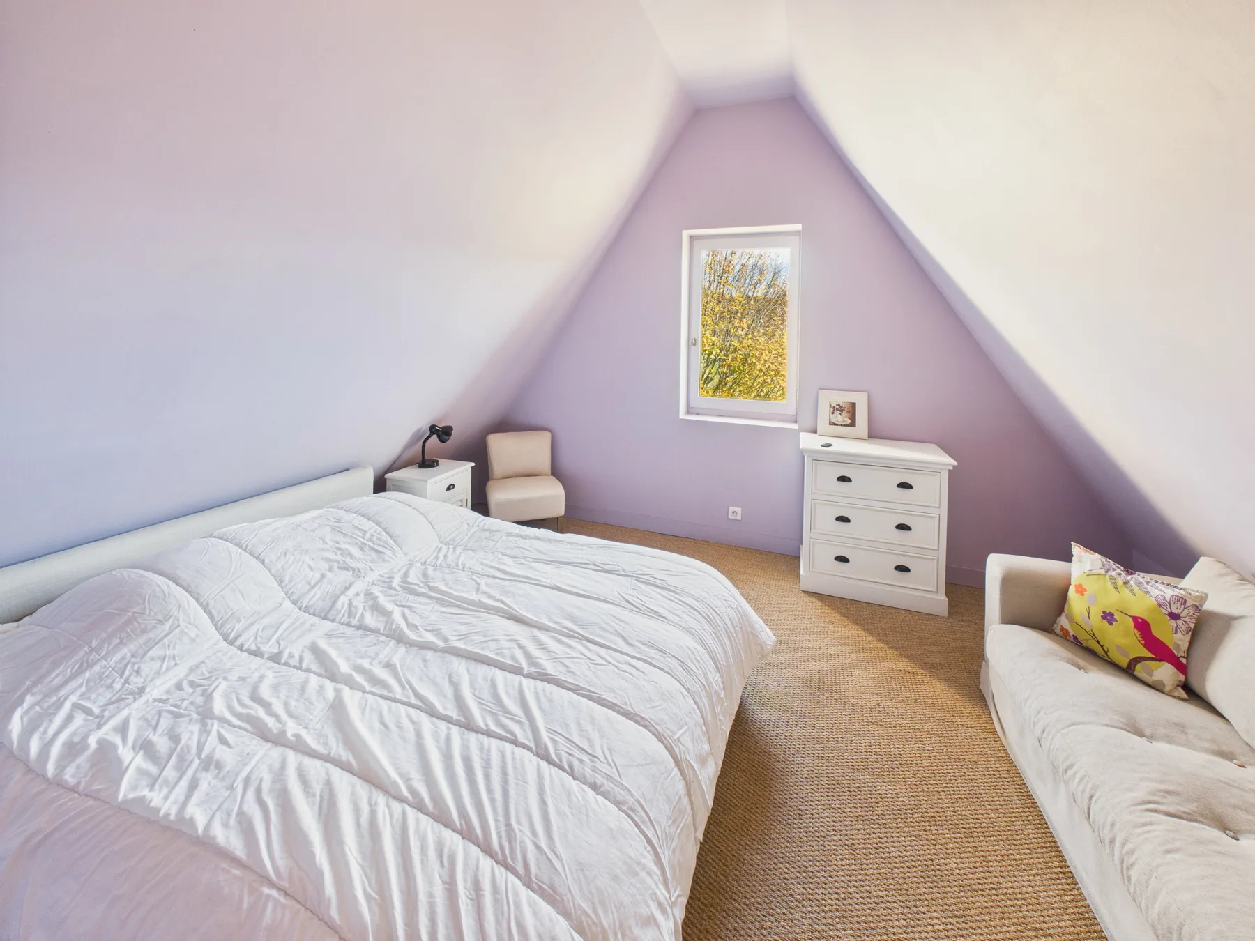 A bedroom with a large bed, a dresser, and a small window.