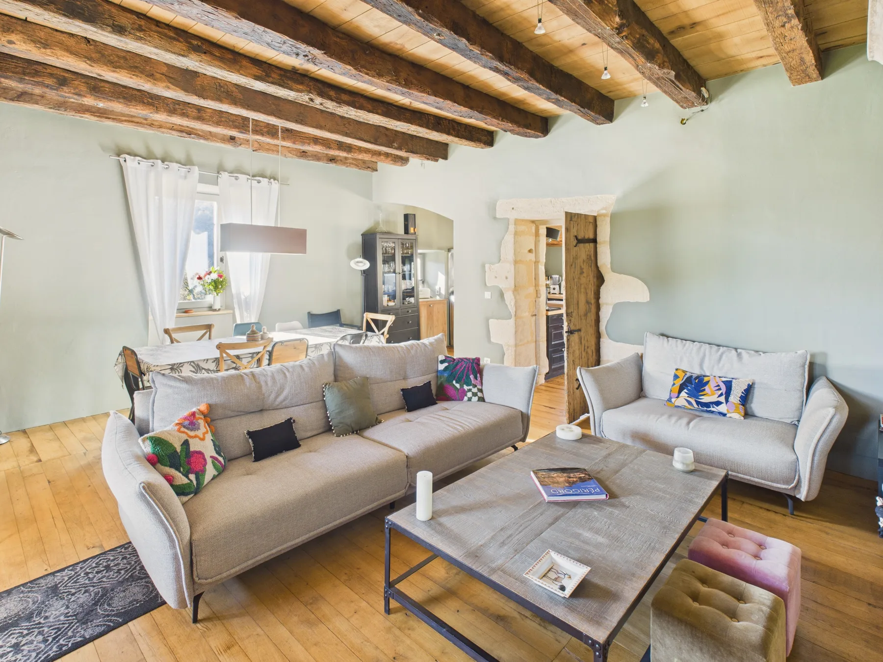 Una sala de estar con asientos tapizados y una mesa de centro bajo vigas de madera expuestas.